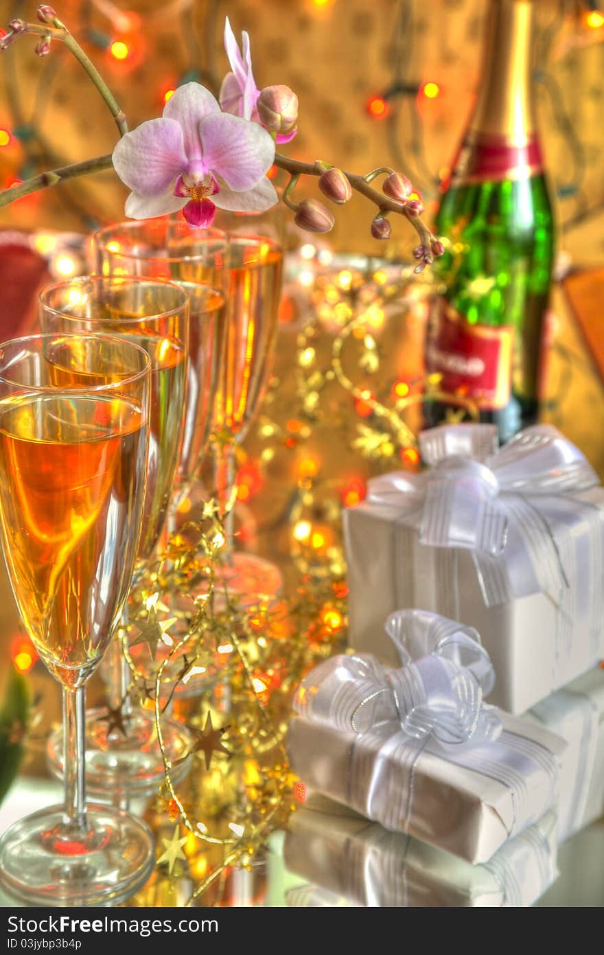 Glasses of champagne,gift boxes,bottle and flowers on gold background. Glasses of champagne,gift boxes,bottle and flowers on gold background.