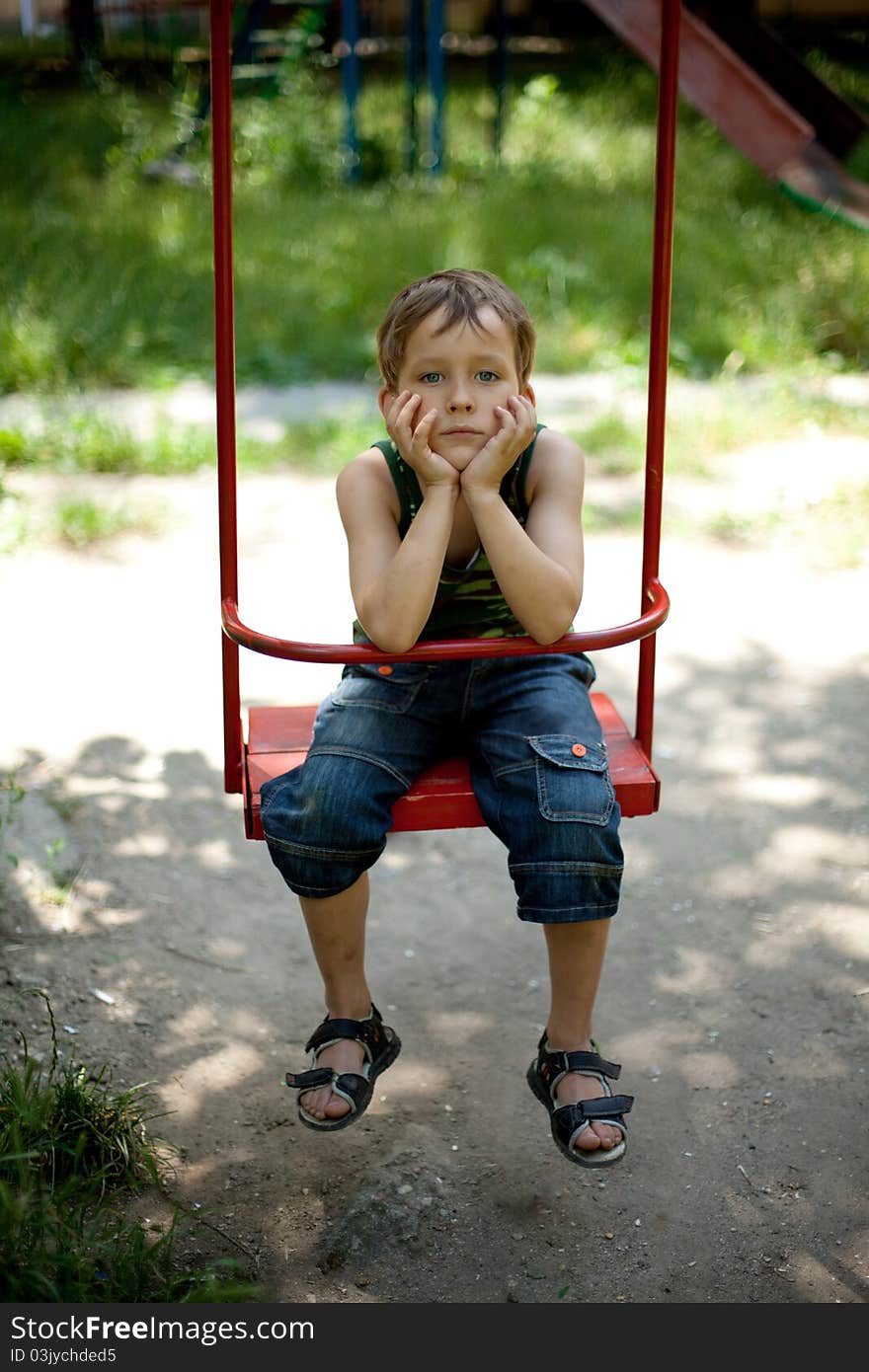 Little boy sitting on a swing