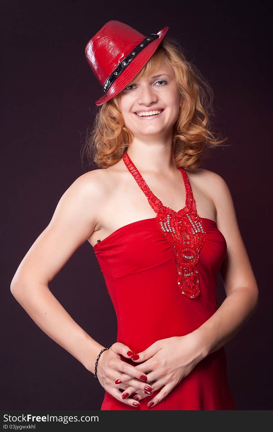 Red-haired girl in a red dress and red hat. Studio photography