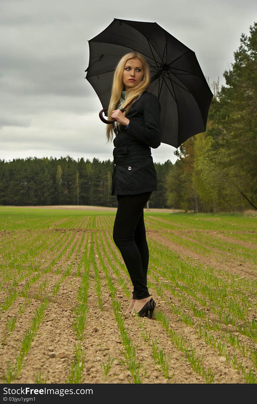 Beautiful blondy girl with umbrella looking back