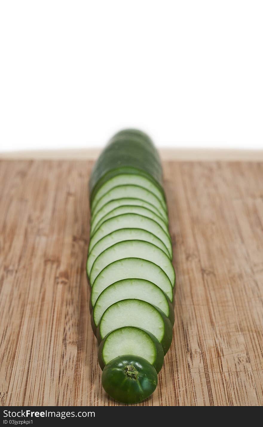 Sliced cucumber vertical on cutting board isolated white background