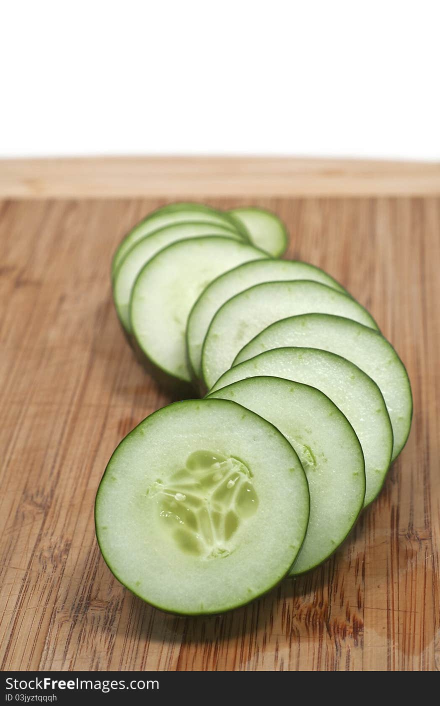 Sliced cucumber in wavy formation vertical isolated white background. Sliced cucumber in wavy formation vertical isolated white background