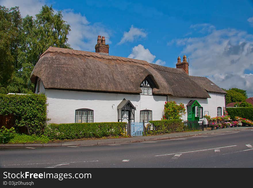 Traditional English country cottage exterior with flowers on display. Traditional English country cottage exterior with flowers on display.