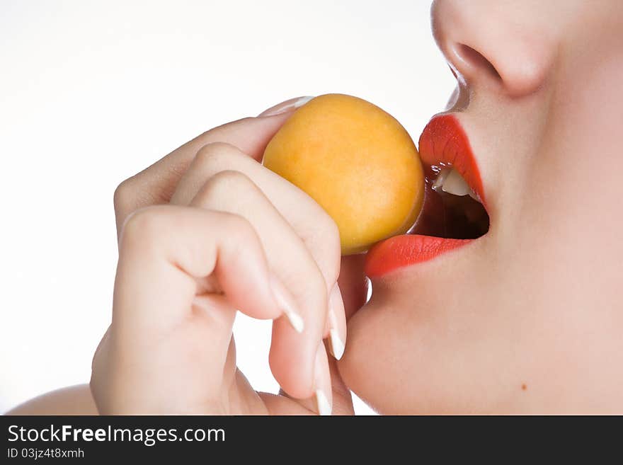 The beautiful girl holds an apricot in teeth. The beautiful girl holds an apricot in teeth