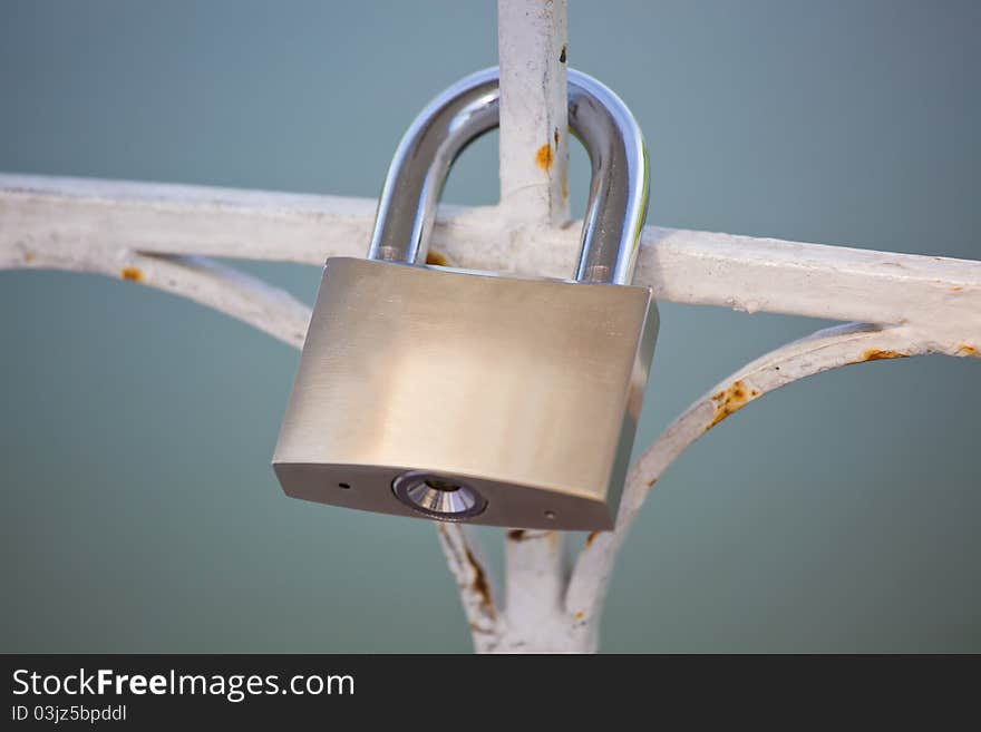 The lock hangs on a metal lattice. The lock hangs on a metal lattice