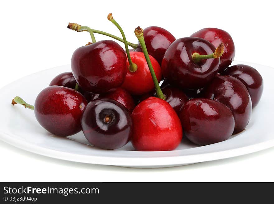 Ripe cherries on a white plate. Isolated on a white background