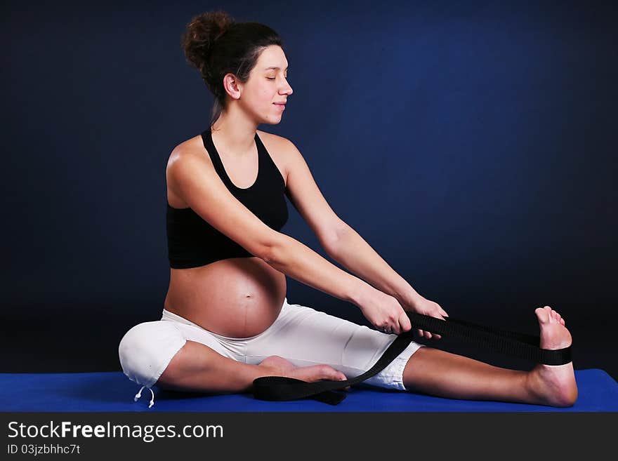 Beautiful pregnant young woman practicing yoga on black. Beautiful pregnant young woman practicing yoga on black
