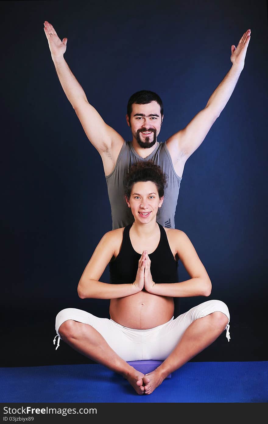 Beautiful pregnant young woman practicing yoga with husband. Beautiful pregnant young woman practicing yoga with husband