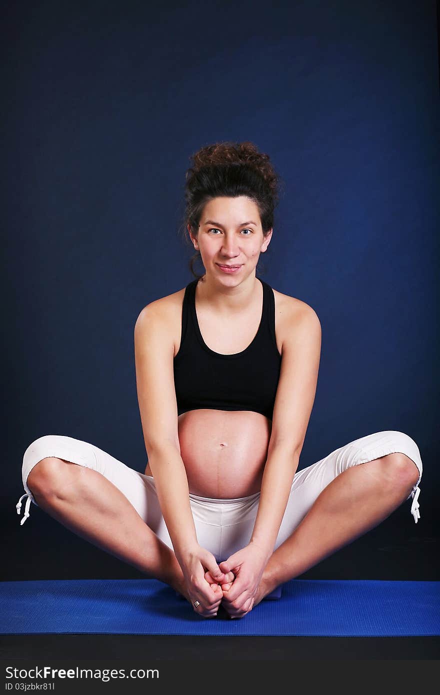 Beautiful pregnant young woman practicing yoga on black. Beautiful pregnant young woman practicing yoga on black