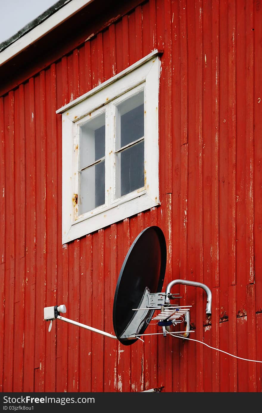 Satellite antenna on wall of small wooden house. Satellite antenna on wall of small wooden house.