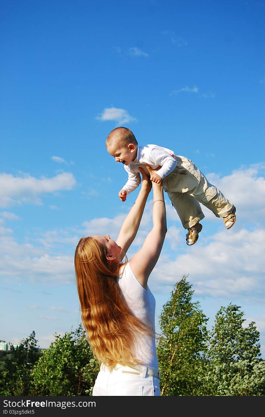 Mother raising baby to the sky. Mother raising baby to the sky