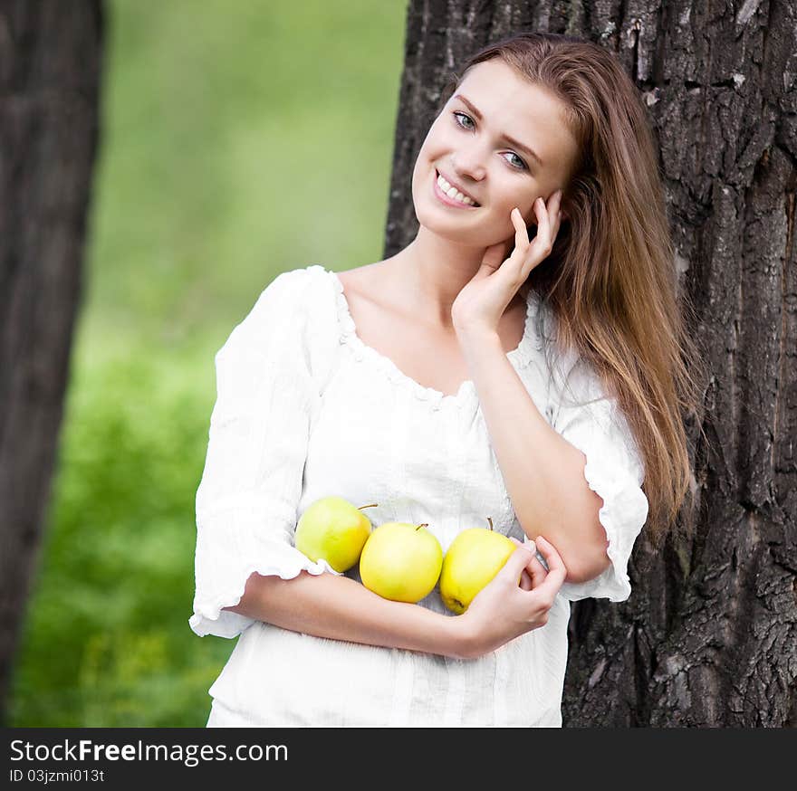 Beautiful happy young woman with apples in the park  on a warm summer day