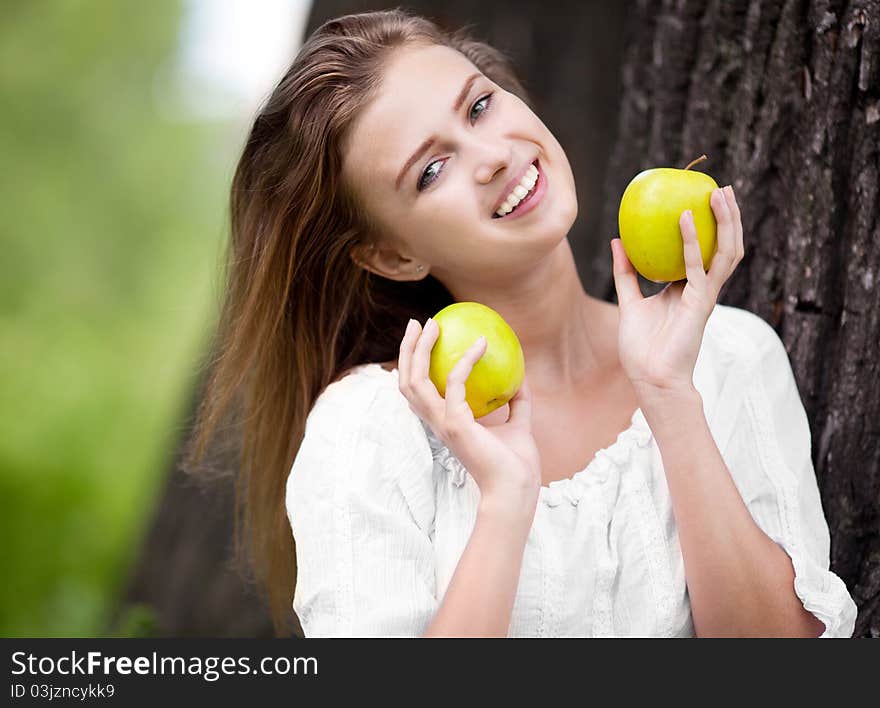 Beautiful happy young woman with apples in the park  on a warm summer day