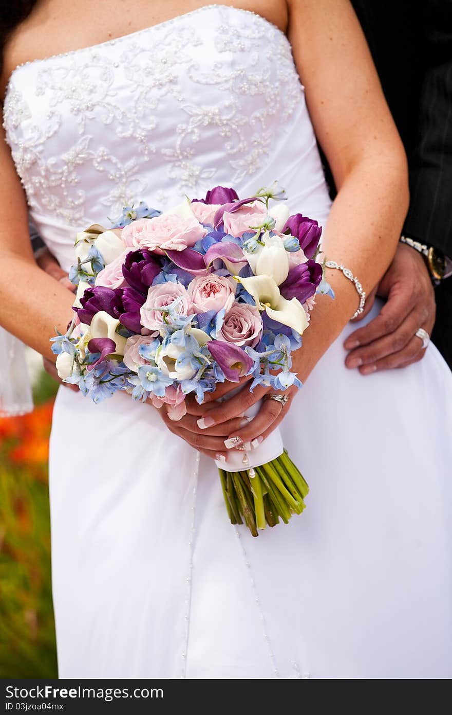 Bride and groom holding bridal bouquet. Bride and groom holding bridal bouquet