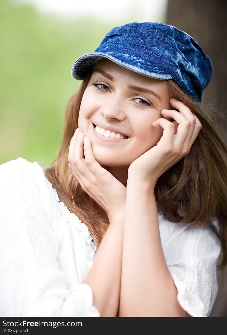 Happy young woman wearing a cap in the park on a warm summer day. Happy young woman wearing a cap in the park on a warm summer day