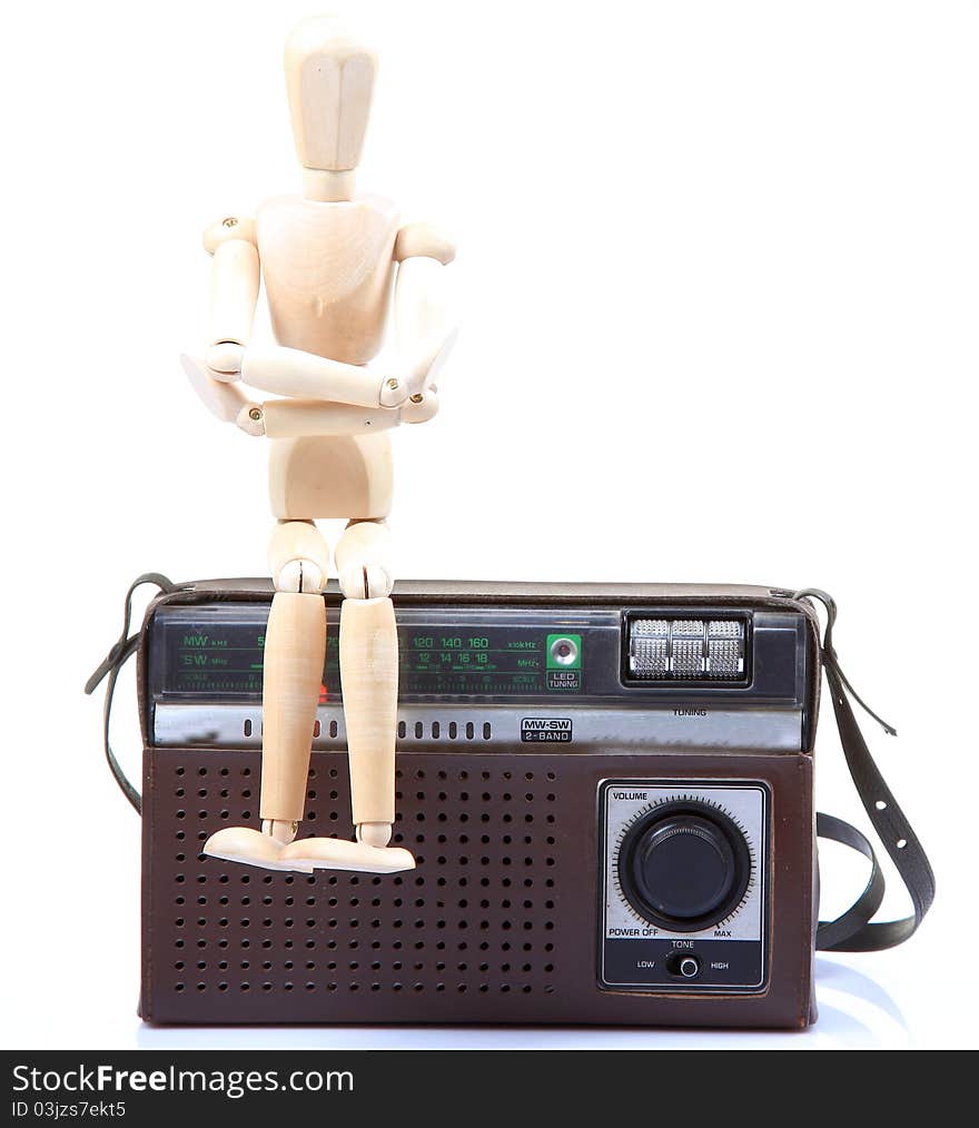 Wooden mannequin sitting on old radio. Wooden mannequin sitting on old radio.