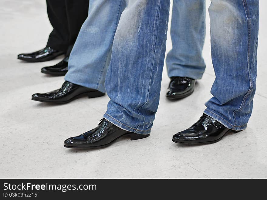 Men's feet in black leather shoes and jeans