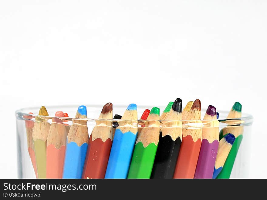 Colored pencils in a glass cup isolated on white