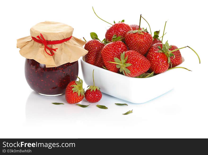 A bowl of fresh strawberries with a jam pot. A bowl of fresh strawberries with a jam pot