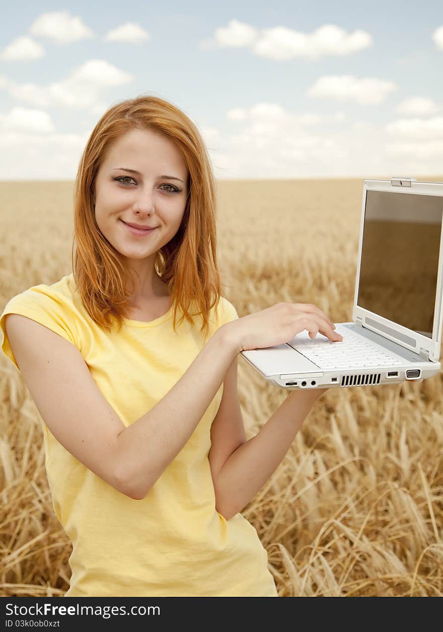 Girl with laptop at wheat field.