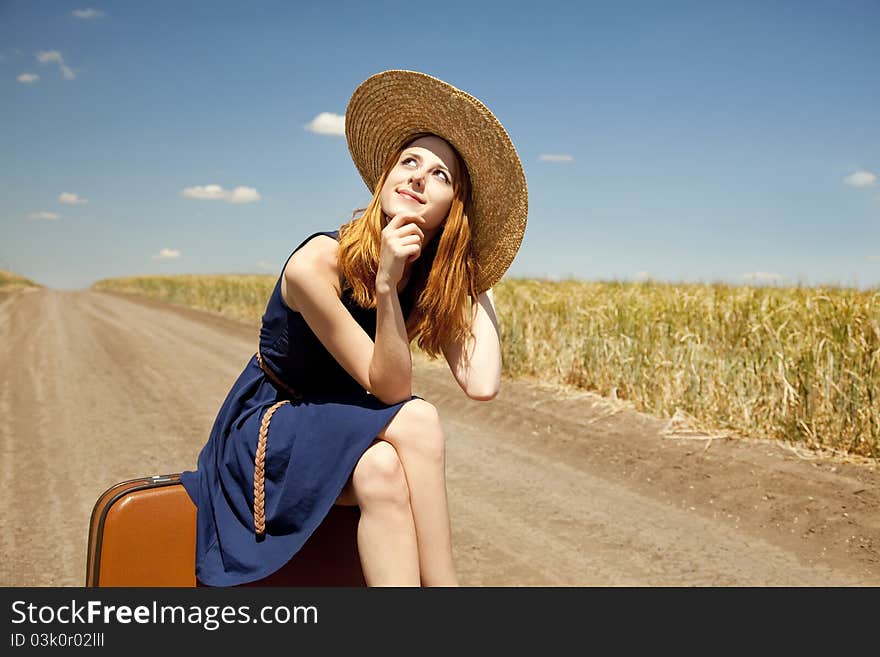 Girl with suitcase at country road.