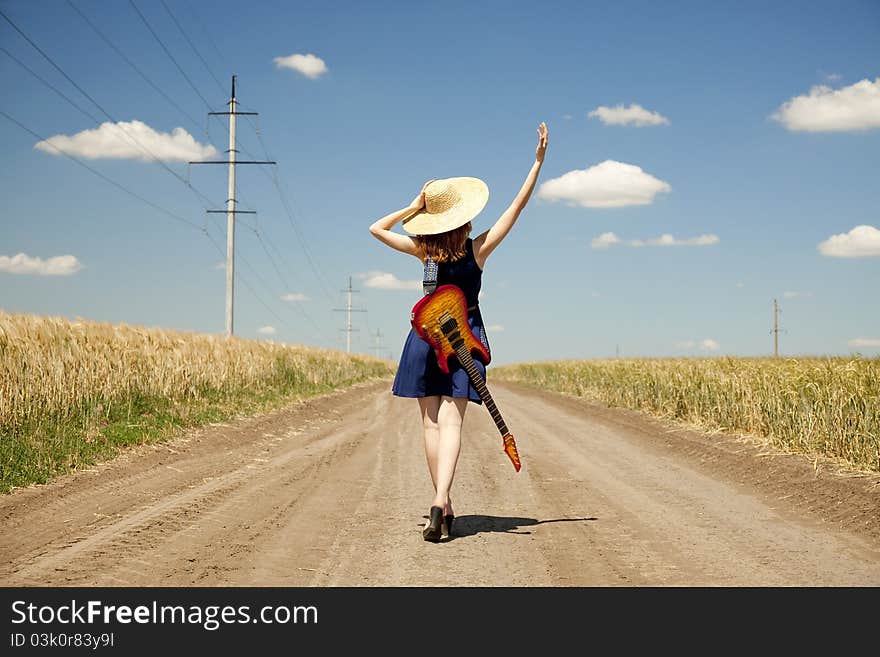 Rock girl with guitar at countryside