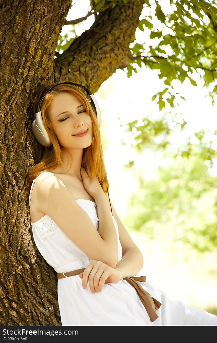 Redhead girl with headphones at garden.