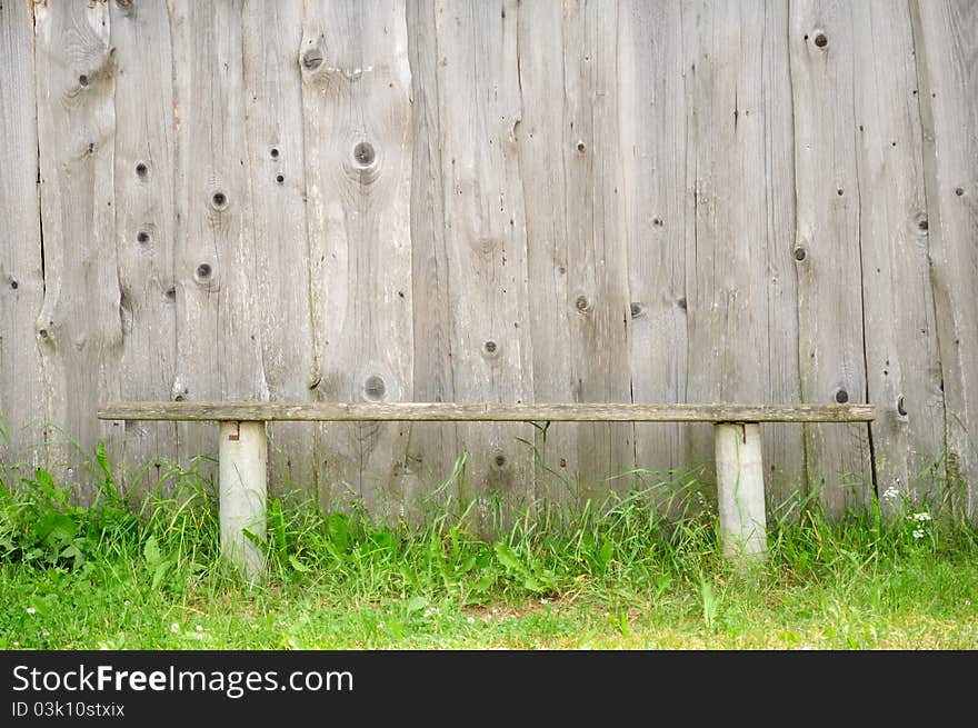 An old bench against an unpainted wooden wall. An old bench against an unpainted wooden wall