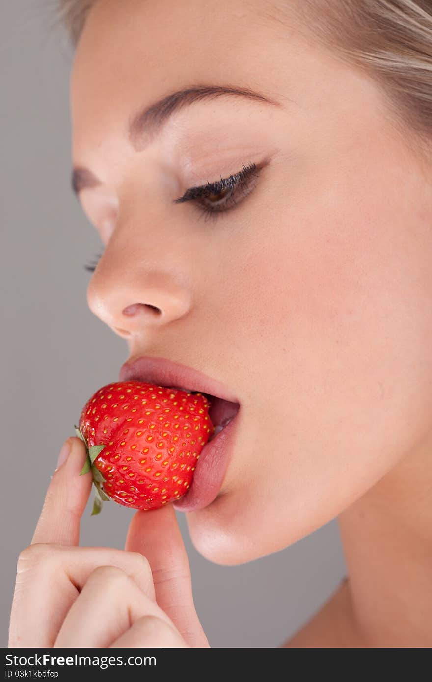 Beauty woman holding astrawberry on grey background