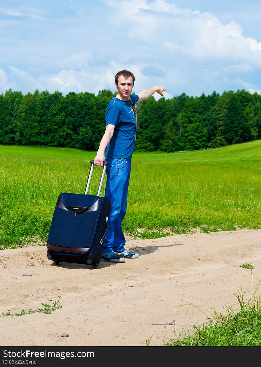 The Young Man On Road In Field With A Suitcase