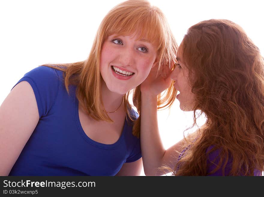 A young beautiful girl is whispering something into her friends ear. A young beautiful girl is whispering something into her friends ear