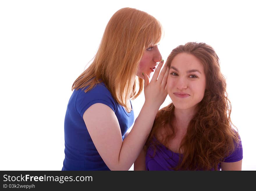 A young beautiful girl is whispering something into her friends ear. A young beautiful girl is whispering something into her friends ear