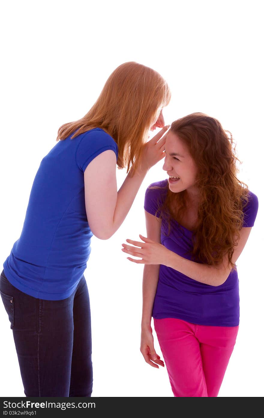 A young beautiful girl is whispering something into her friends ear. A young beautiful girl is whispering something into her friends ear