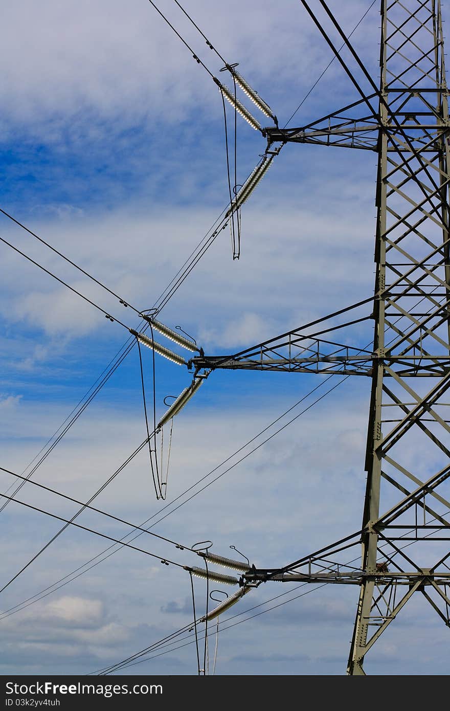 A metal electricity pylon against a blue cloudy sky. A metal electricity pylon against a blue cloudy sky