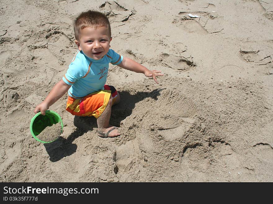 Boy holding a bucket of sand on the beach. Boy holding a bucket of sand on the beach.