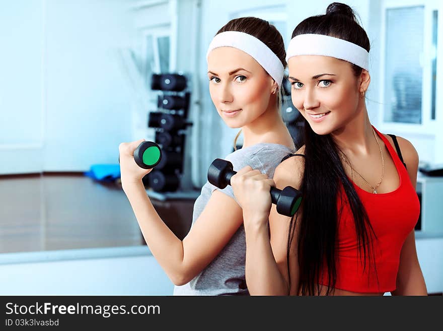 Two young sporty women in the gym centre.