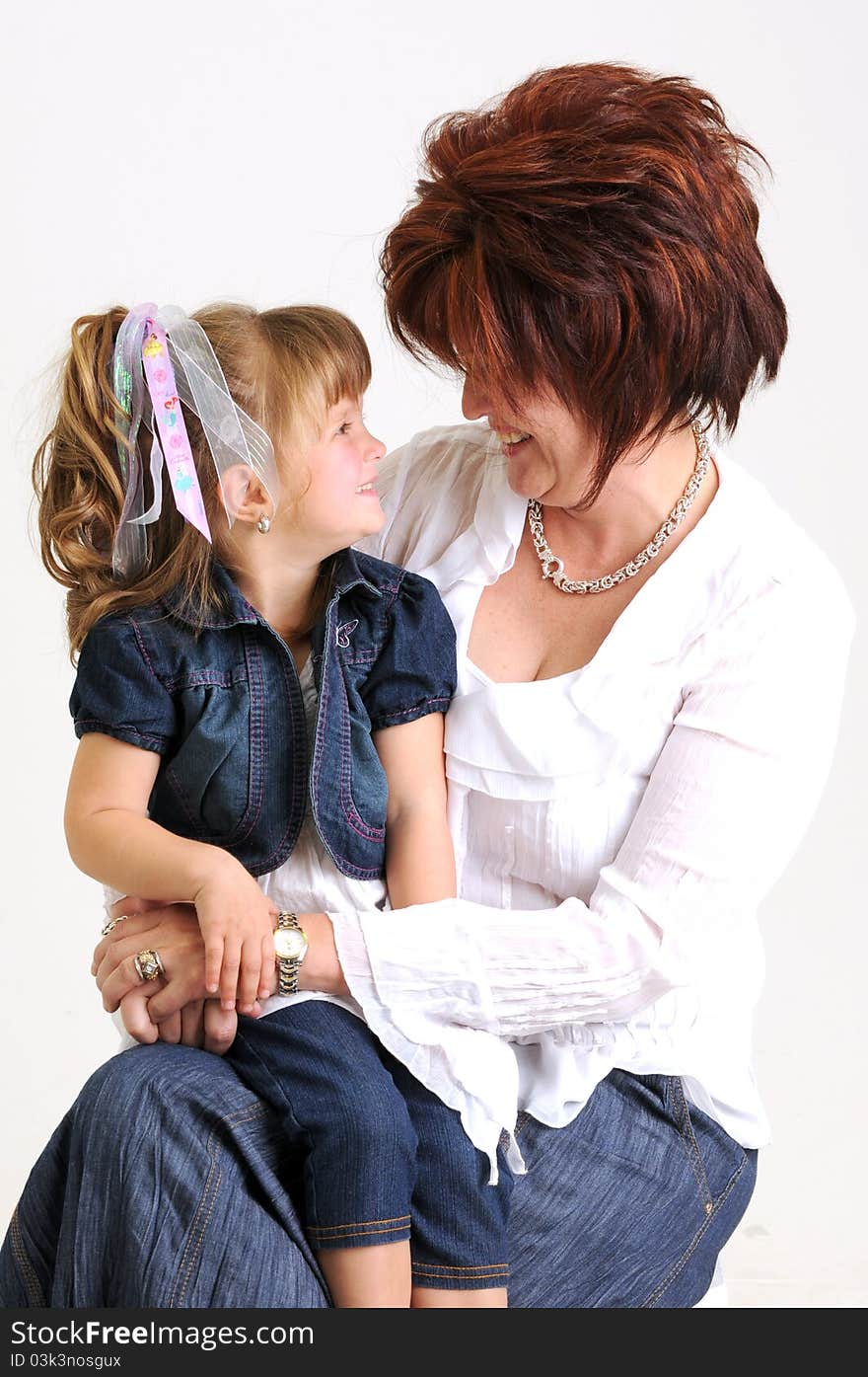 Young daughter and mother dressed in blue and white smiling. Young daughter and mother dressed in blue and white smiling