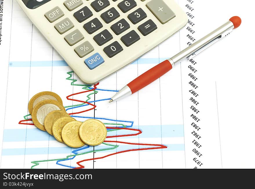 Calculator, coins and pen laying on chart.