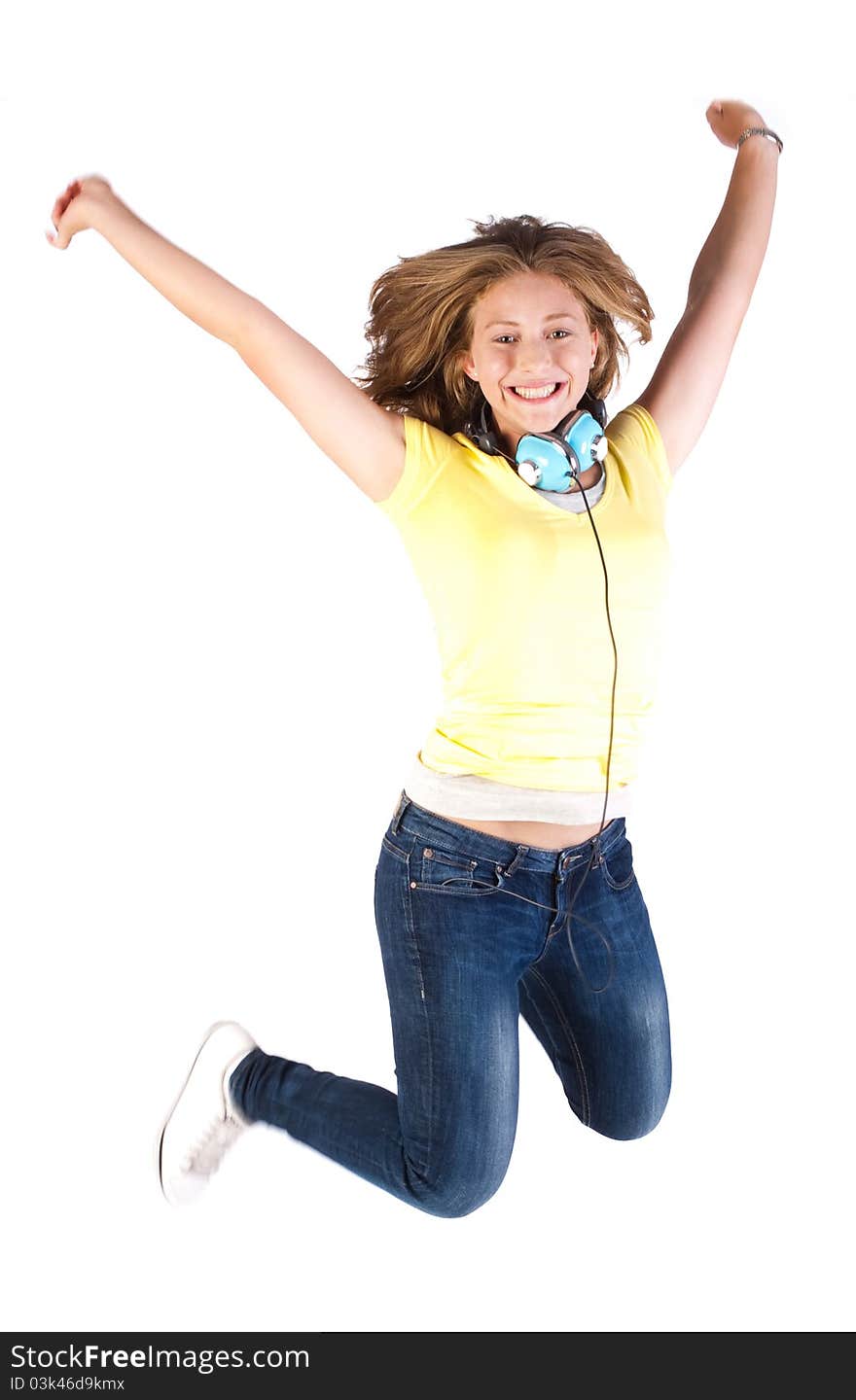 Girl jumping high with headphones around her neck, indoors.