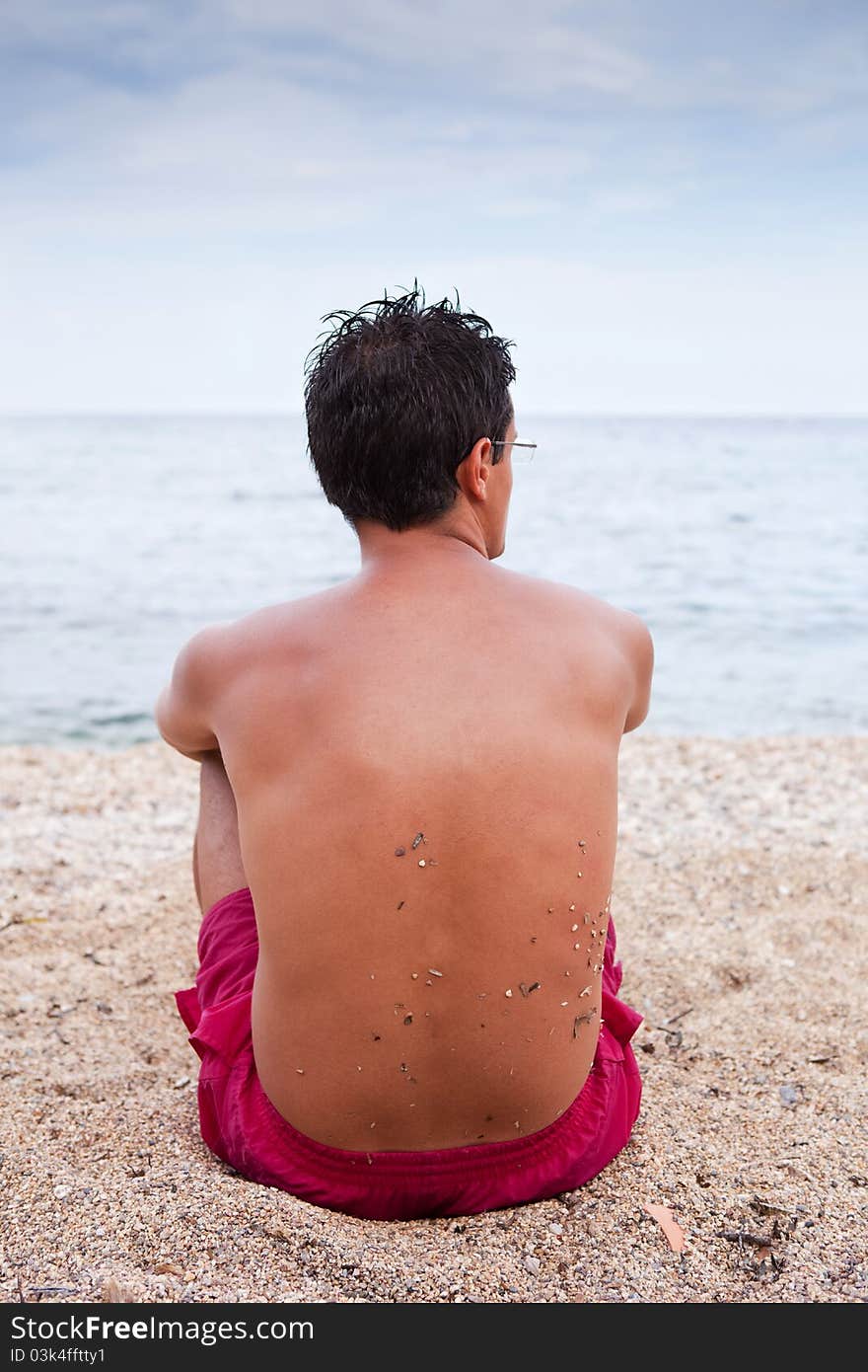 Young man sitting alone on the beach