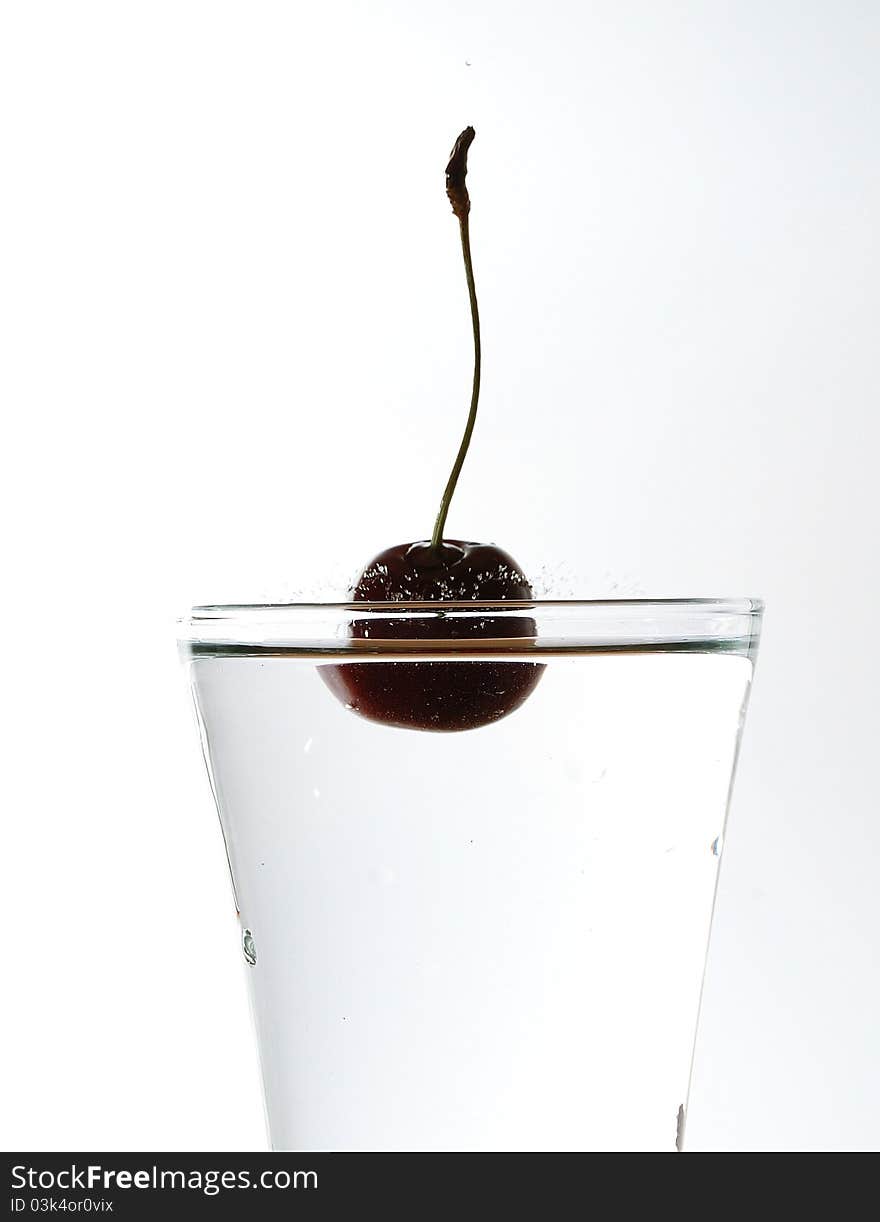 Splash with cherries in glass full of water. Splash with cherries in glass full of water