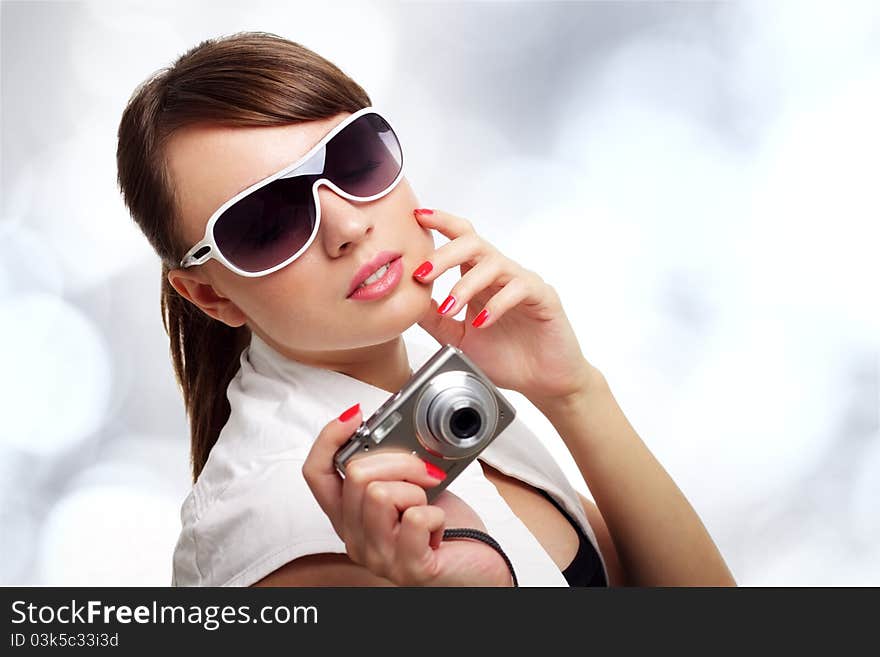 Young stylish woman with a camera on a light background