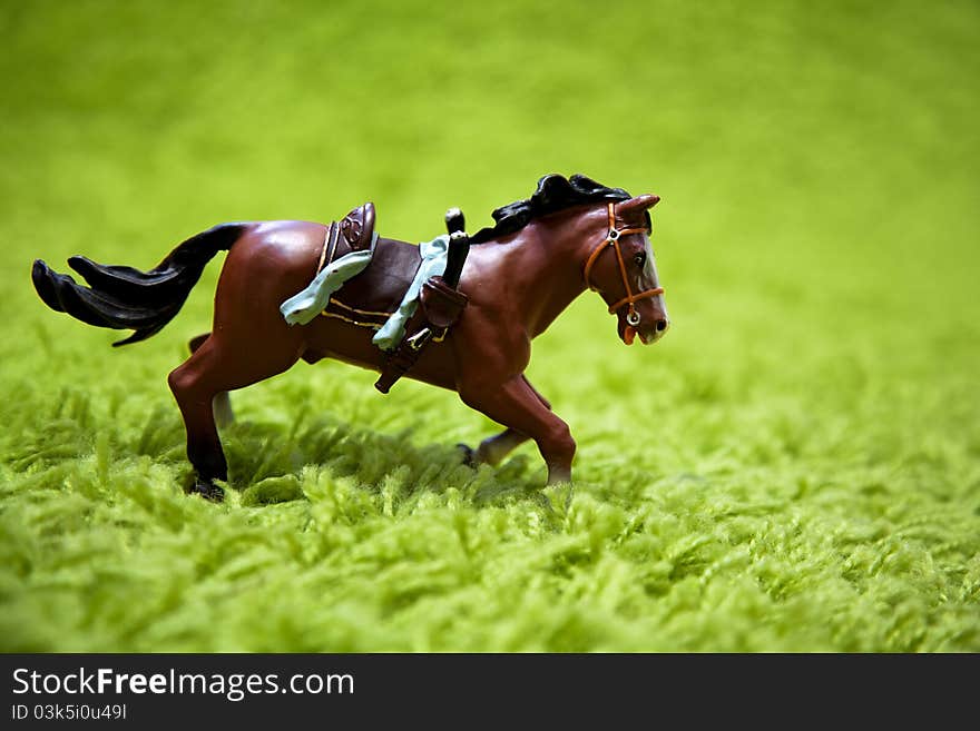 Miniature toy horse in running posture on a carpet like grass. Miniature toy horse in running posture on a carpet like grass