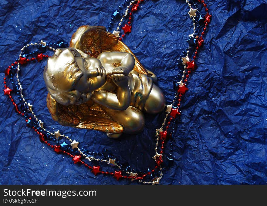 Praying angle in a middle of red white and blue necklace heart on dark blue background. Praying angle in a middle of red white and blue necklace heart on dark blue background