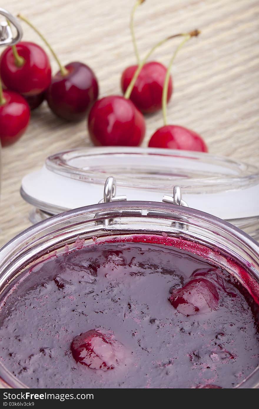 Studio-shot of homemade cherry jam in a glass jar.