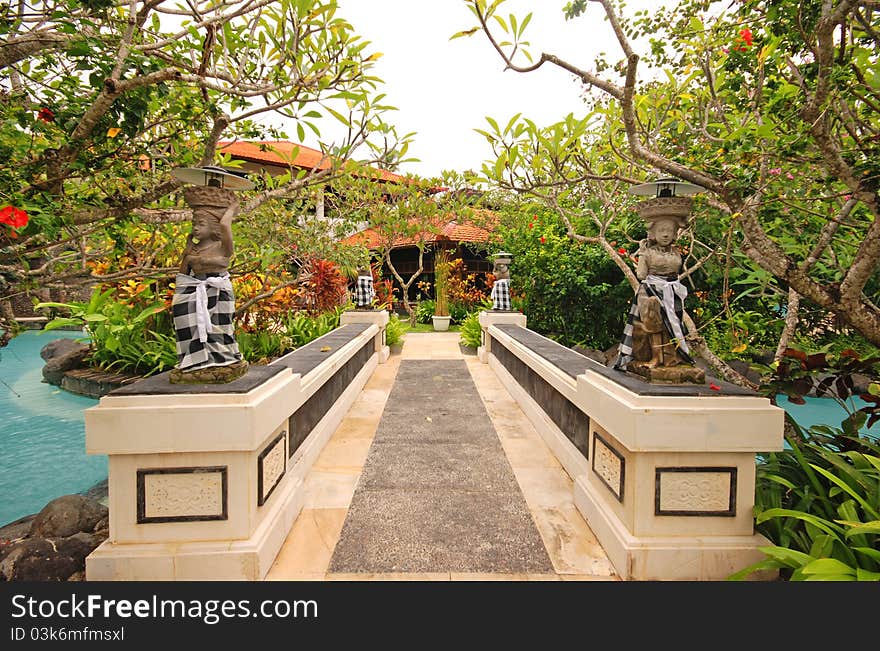 Bridge with traditional statues in beautiful garden on luxury tropical resort. Bali, Indonesia. Bridge with traditional statues in beautiful garden on luxury tropical resort. Bali, Indonesia.