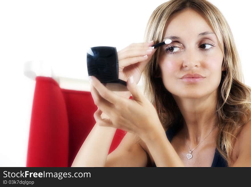 Blond woman applying eye shadow to her eyes. Blond woman applying eye shadow to her eyes