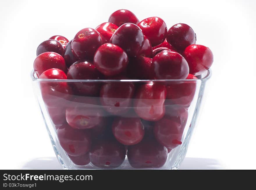 A pile of fresh large cherries in a small bowl on a white background. A pile of fresh large cherries in a small bowl on a white background