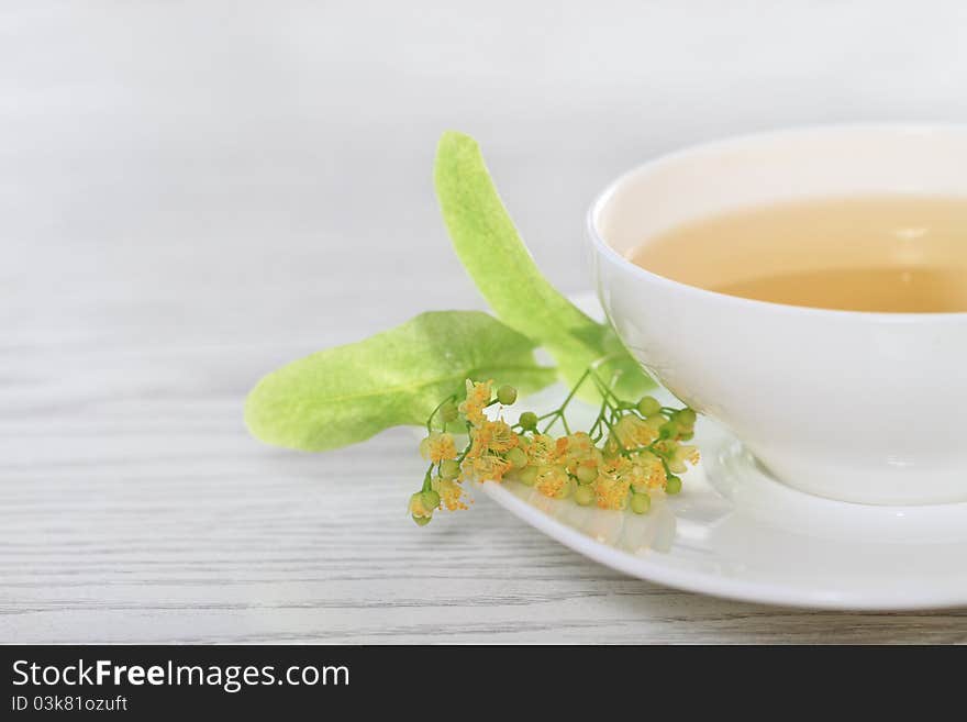 Cup of the linden tea on white wooden background. Cup of the linden tea on white wooden background