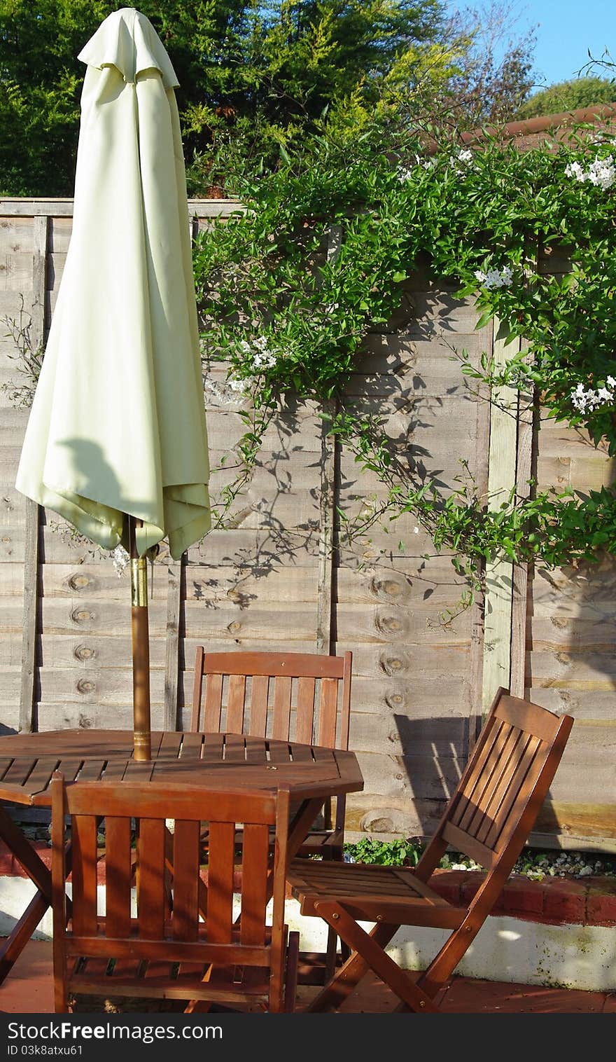 Wooden table and chairs with parasol on patio in garden. Wooden table and chairs with parasol on patio in garden